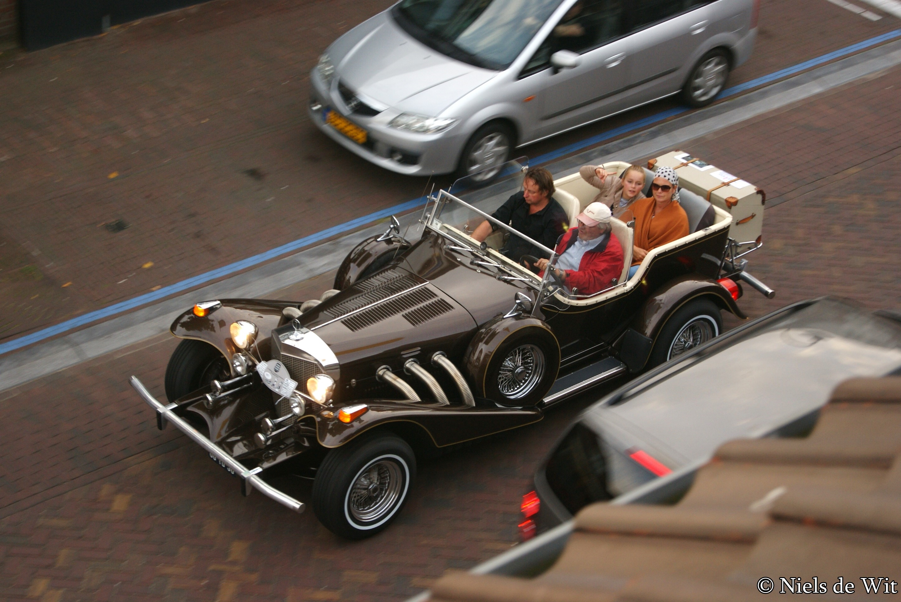 Excalibur Phaeton Series III fra 1976 med lang motorhjelm og fritstående forlygter ved et biltræf.